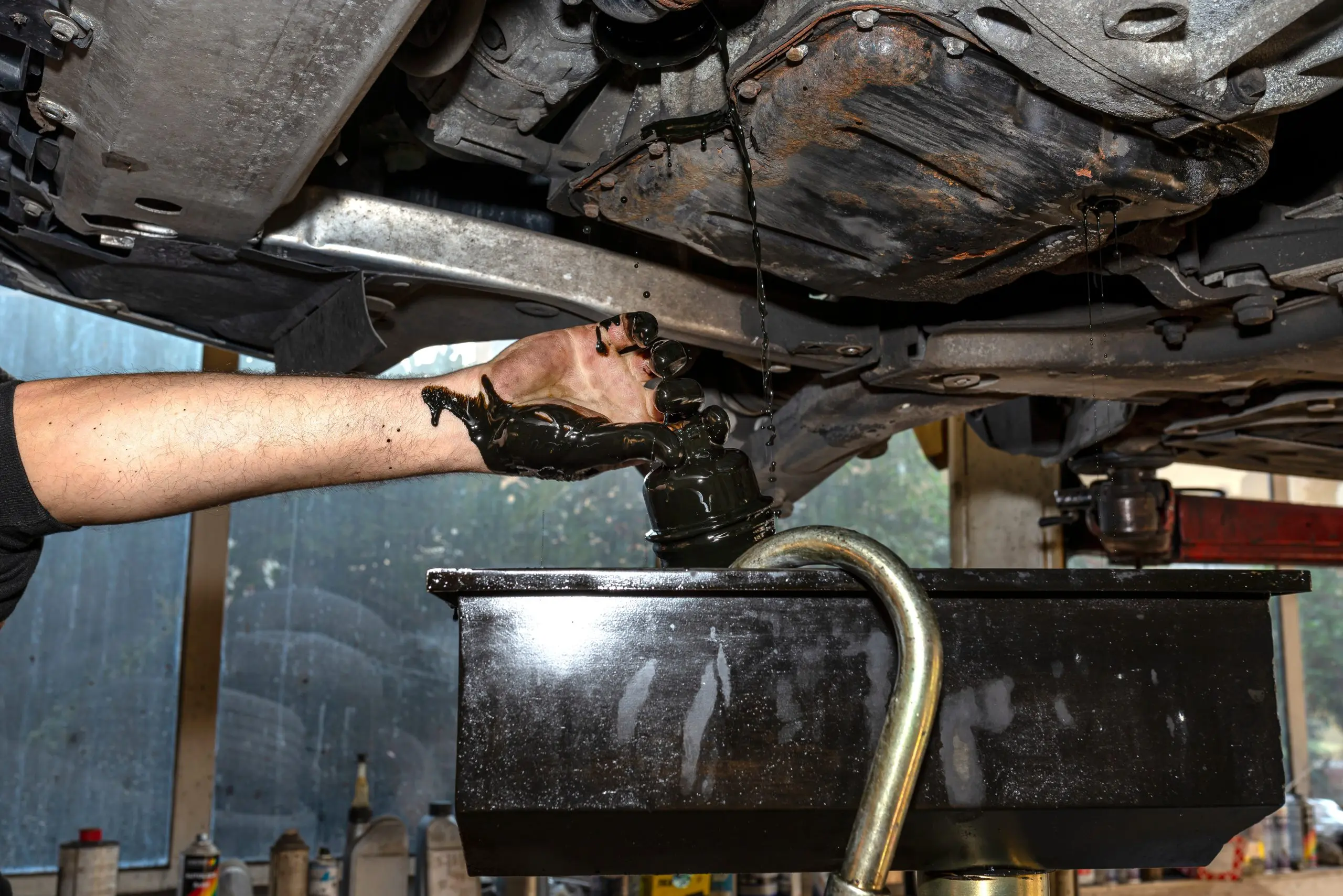 The car mechanic unscrews the diesel oil filter next to the oil pan, old black oil drains into the container. Image of a pipe join waiting to be powder coated with masking to prevent the openings being powder coated.